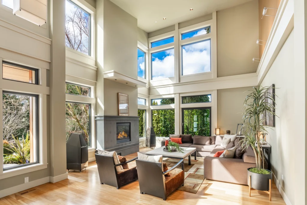 Modern living room setup with space-saving furniture layout, featuring a sectional sofa, armchairs, and a fireplace under a high ceiling.
